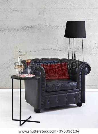 Black chesterfield arm chair and floor lamp on stone wall background, still life