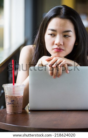 Asian woman boredly using a notebook