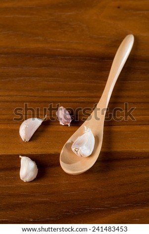 Garlic with wooden spoon on wood table surface