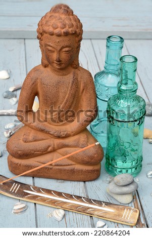 Buddha with incense and green blue bottles