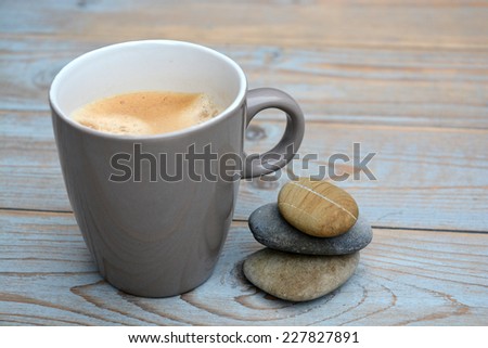 Grey coffee mug with zen stones on old wood