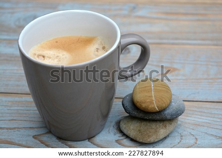 Grey coffee mug with zen stones on old wood