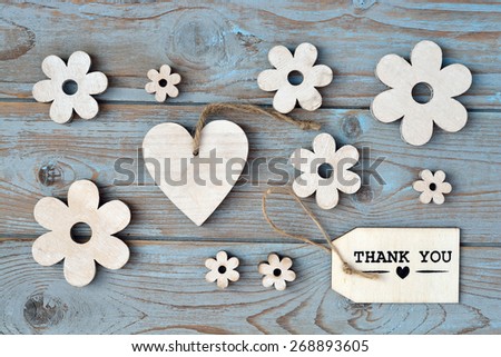 Blue grey wooden background with label with thank you text and wooden flowers and heart