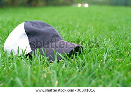 gray baseball cap on a green lawn as a symbol of active lifestyle