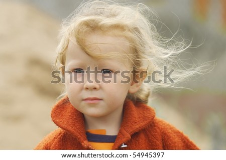 Portrait of a little girl. The wind blows her long thin hair. Shallow DOF.