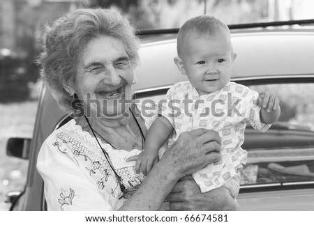 The old grandmother holds the little grand daughter and smiles. Shallow DOF.