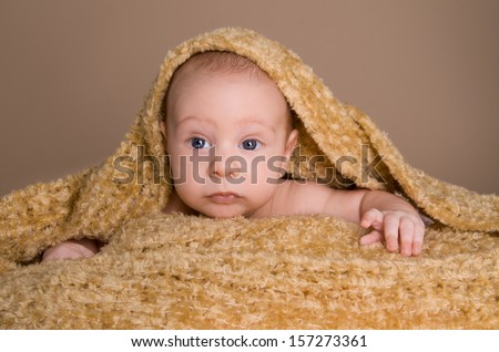 newborn baby wrapped in  light brown soft fluffy cloth on beige background