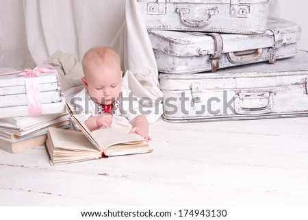 Boy near retro book on white painted floor