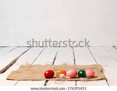 Easter colored eggs lie on canvas on wooden white floor