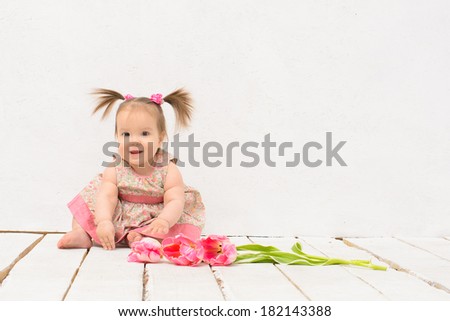 baby girl in pink dress with flowers sitting on wooden floor of painted in white