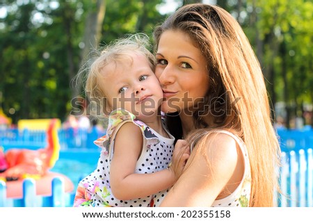 Mother kisses daughter for a walk in the park