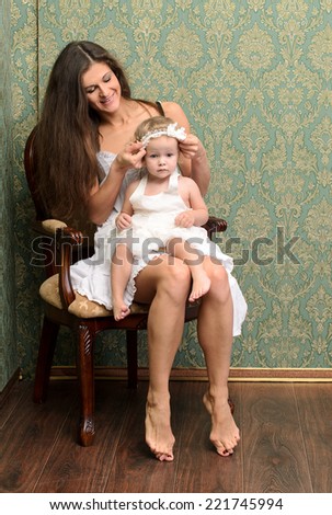 mother with daughter sitting in armchair in retro style
