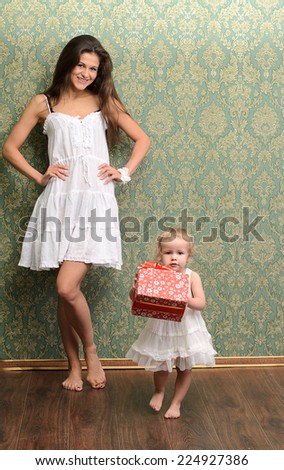 young mommy and little daughter with gift in family style