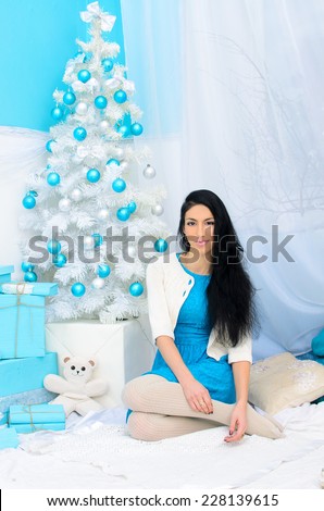 brunette girl at new year tree in white and blue colors
