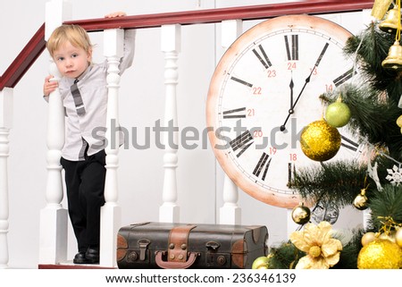 little boy at stair rails with big clock in christmas interior