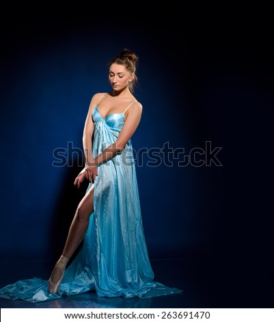 Ballerina in dance pose before dancing. In blue flying dress, studio shooting