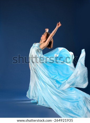 Ballet dancer in flowing light dress on  blue background