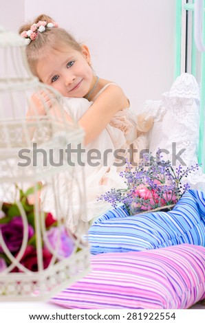 little girl with birdcage and flowers in home interior