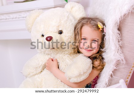 little cute girl embracing big white teddy bear indoors