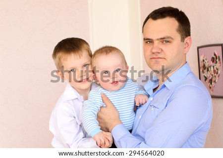 portrait of young daddy and two little sons indoors