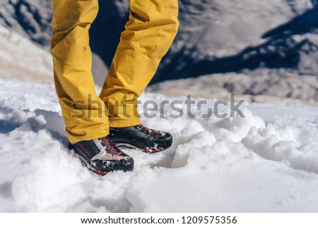 Detail close up shot of hiking or trekking shoes on snow. Technical outdoor boots on a glacier. Mountaineering or climbing winter shoes product photo.