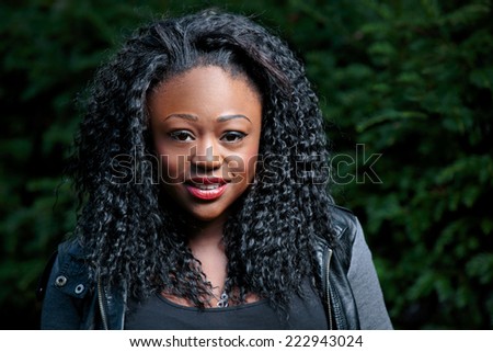 Close Up Smiling Young Black Curly Woman with Green Garden Background.