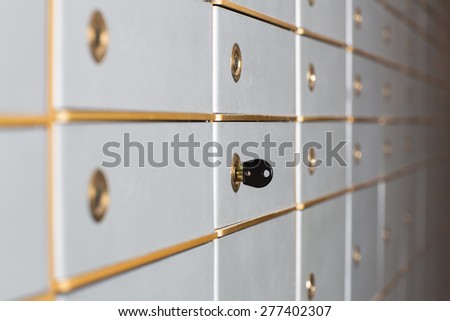 Rows of safety deposit boxes in a bank vault or security lockers with a receding perspective and a key in the lock of one of the doors
