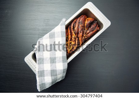 High Angle View of a Tasty Bread Cake on a Tin Tray with Cloth on Top, Placed on a Gray Wooden Table.
