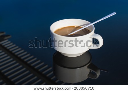 White ceramic coffee mug on blue glass