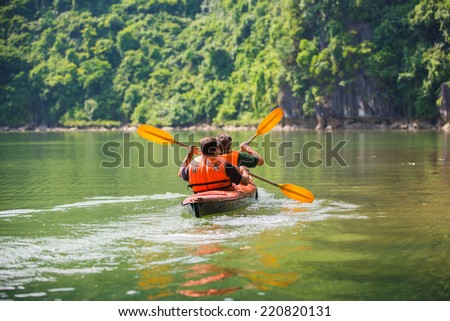 Two men paddle a kayak on the sea. Kayaking in Ha Long Bay