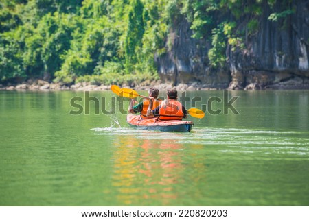 Two men paddle a kayak on the sea. Kayaking in Ha Long Bay