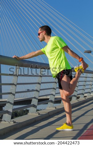 Urban jogger on a big bridge, stretching after running.