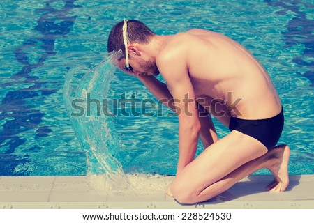 Swimmer splashing water on his face before entering the pool.