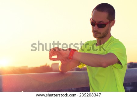 Urban jogger on a big bridge checking his running time.