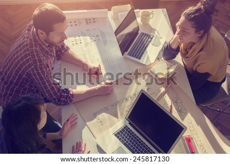 Young group of architects discussing business plans in a natural lit office.
