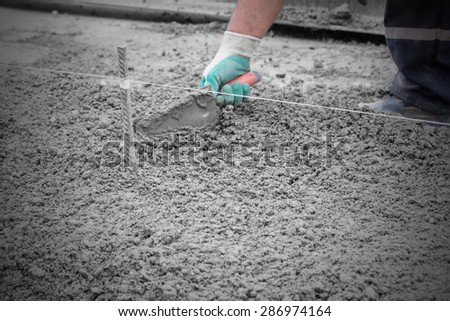 Construction worker leveling concrete pavement. Hand and tool are in motion.