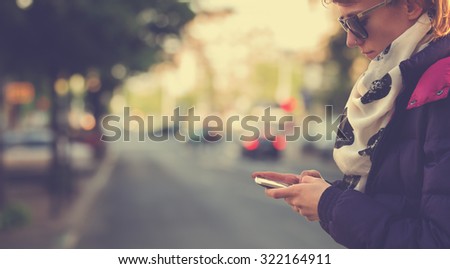 Using cellphone outdoors - with defocused city traffic.