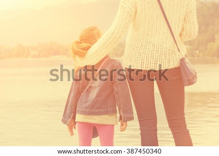 Mother and daughter enjoying sunset on a lake.