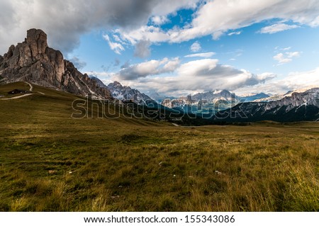 Typical alpine meadow framed by rocky alpine massifs, Dolomites, Italy.