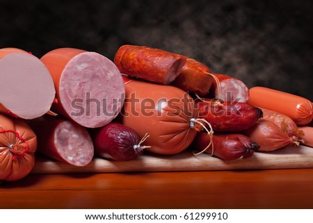 A variety of processed cold meat products, on a wooden cutting board.