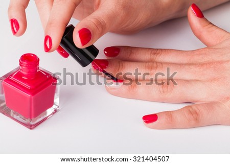 Painting polish on fingers with red nails