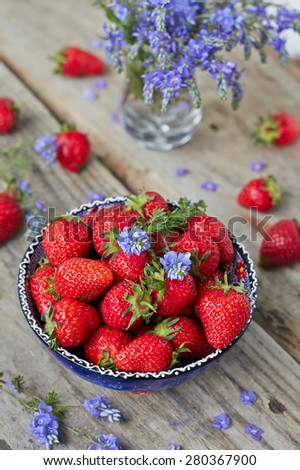 Bowl filled with  juicy fresh ripe red strawberries on an old wooden textured table top