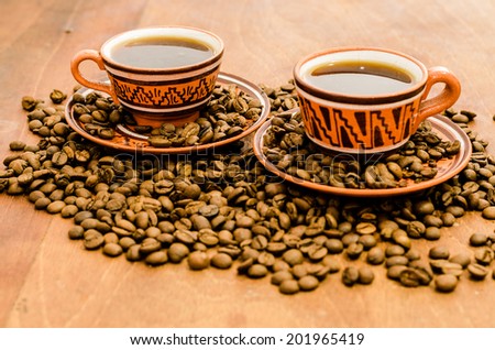 Coffee with steam, without steam, with coffee beans and rustic look on a wooden table. A set with a cup with coffee with coffee grain including cookies / biscuit