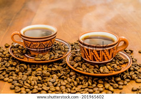 Coffee with steam, without steam, with coffee beans and rustic look on a wooden table. A set with a cup with coffee with coffee grain including cookies / biscuit