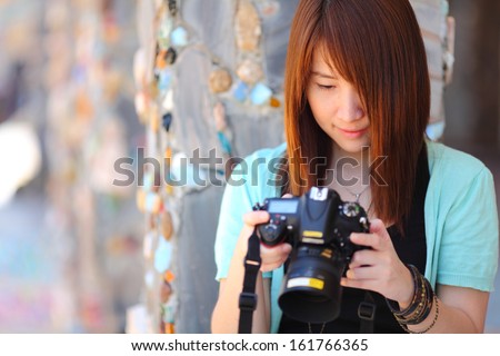Portrait of beautiful smiling girl,with digital camera in her hands,tone in warm color