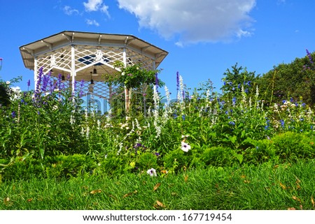 green garden with flowers and a white gazebo.