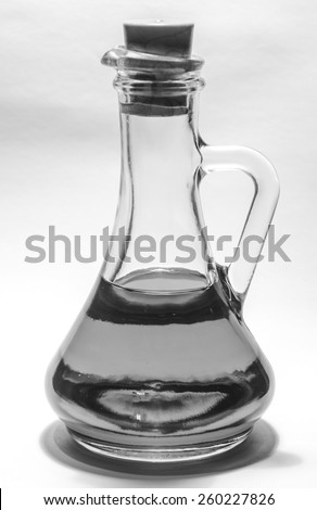 Vegetable oil in a transparent bottle decanter with stopper on the white background black-and-white