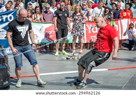 Lviv, Ukraine - July 2015: Yarych street Fest 2015. Strong athlete teeth to pull the chain that fastened the car