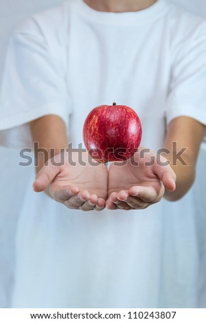 apple levitates above the hands  in the air on a white background