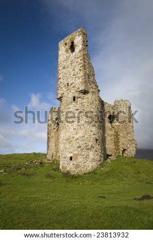 Ruin of ancient Scottish castle with green grass in front and blue cloudy sky in the background, vertical